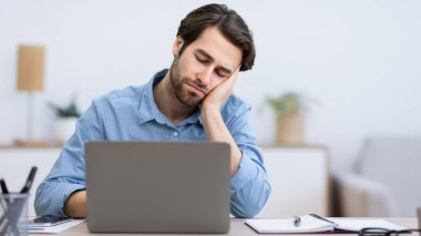 Modern ofisteki iş yerinde dizüstü bilgisayarda uyuyan yorgun iş adamı. Uykusuzluk ve yorgunluk sorunu, sıkıcı iş kavramı. Seçici Odaklanma
