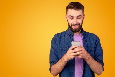 İnternette gezinen, internetten iletişim kuran ya da turuncu arka plan üzerinden alışveriş yapan sakallı yakışıklı bir adam. Cep telefonu kullanarak çalışan ya da uzaktan çalışan genç adam