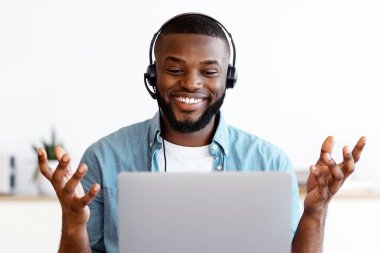 Video çağrısı. Neşeli Afrikalı Amerikalı adam evde dizüstü bilgisayarla çevrimiçi görüşüyor, siyah serbest çalışan adam bilgisayarda web konferansı yapıyor, çevrimiçi iletişimin tadını çıkarıyor.