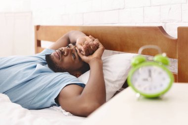 Uyku bozukluğu. Geceleri, kopya alanı onun sorunları hakkında düşünme genç Afro-Amerikan adam yatakta uykusuzluk, acı