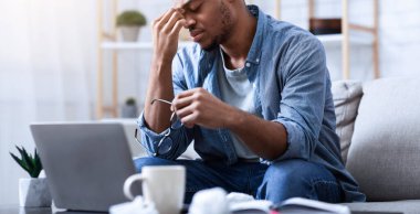 Gözler yorgunluğu. Siyah adam, işten sonra evdeki koltukta otururken burun köprüsüne masaj yaparken sorun yaşıyor. Göz Hastalığı ve Glaucoma Hastalığı Konsepti. Seçici Odaklanma