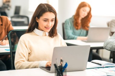 Eğitim ve Teknoloji Konsepti. Sınıfta bilgisayar kullanan gülümseyen bir kadının portresi, lise için çevrimiçi proje yapıyor, dizüstü bilgisayarda araştırma yapıyor ve internette geziniyor.