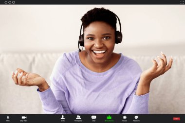 Uzaktan Çalışma ve Teknoloji. Siyah kadın, video konferansı yaparken kulaklık takıyor, sanal internet görüşmesi sırasında kamerayla konuşuyor. Video Çağrı Arayüzü, Uygulama Görüntüleme, Videotelephony ve Telekomünikasyon