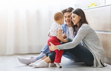 Aile eğlencesi. Neşeli anne ve baba mutfak zemininde oğluyla oynuyorlar.