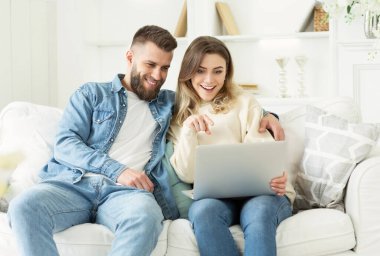 Mutlu çift dizüstü bilgisayar kullanarak ve izlemek için film seçerek, evde hafta sonu zevk