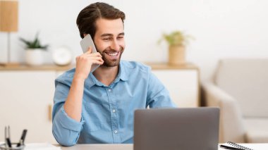 Gladful Man telefonda konuşuyor. İnternette bilgisayarda çalışıyor. Modern ofiste masasında oturuyor. Serbest Çalışan Adam içeride cep telefonuyla konuşuyor. Modern Mobil İletişim Konsepti