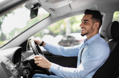 Resmi kıyafetli neşeli sakallı adam yola bakıyor ve gülümsüyor, güzel bir otomobil sürüyor, genç orta doğulu iş adamı ofise gidiyor, yan görüş, fotokopi odası, güneş ışığı...