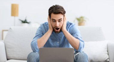 Bilgisayar başındaki şoke olmuş iş adamı evde koltukta otururken çalışırken sorun yaşıyor. Uzaklık Çalışma Sayısı ve İnternet Bağlantı Sorunları