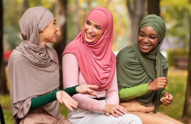 Hijab 'da üç Arap kadın şehir parkında bankta oturmuş sohbet etmekten keyif alıyorlar. Hafta sonu tatili, Müslüman Kadınlar Arkadaşlarla Buluşuyor. Kadın Arkadaşlığı Konsepti