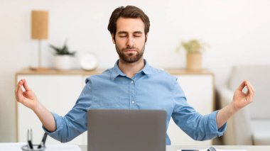 Sakin ol. İşadamı ofiste meditasyon yapıyor, laptopun başında gözleri kapalı oturuyor iş stresi için evde rahatlıyor. İşyeri Meditasyonu ve Rahatlama Egzersizleri Konsepti. Seçici Odaklanma