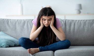 Covid bağlantılı gençlik depresyonu kavramı. Evdeki kanepede oturan mutsuz Hintli genç kız, iletişim ve yalnızlık eksikliğinden muzdarip, tecrit sırasında stresli hissediyor.