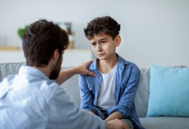 Baba ve üzgün oğul evde kalp kalbe konuşuyorlar, baba sorunları çözmeye çalışıyor, birlikte çözüm arıyorlar. Ebeveyn sevgi ve özen gösteriyor, çocuğu sakinleştiriyor ve omuz omuza tutuşuyor.