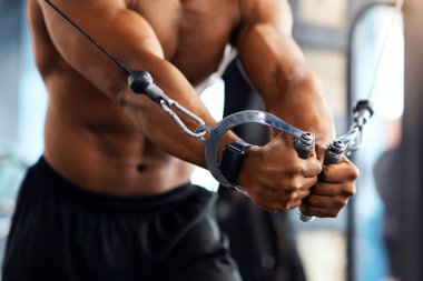 Spor salonunda, fotokopi alanında triseps çalıştıran siyah bir adam. Tanımlanamayan Afrikalı Amerikalı vücut geliştirici modern spor salonunda çalışıyor, çapraz makine kullanıyor.