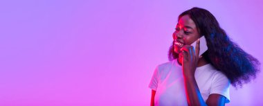 Gülümseyen genç Afrikalı Amerikalı kadın cep telefonuyla neon ışıkta konuşuyor, afiş tasarımı ve fotokopi alanı. Güzel siyahi bayan müşteriyle ya da arkadaşıyla akıllı telefondan konuşuyor.