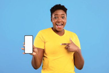 Heyecanlı Siyah Kadın Mavi Stüdyo Arkaplanı Üzerinde Akıllı Telefonu Kamera Öneren Uygulamayı Gösteren Boş Ekran 'ı Gösteriyor. Cep telefonu kavramı için harika bir cep telefonu uygulaması. Model