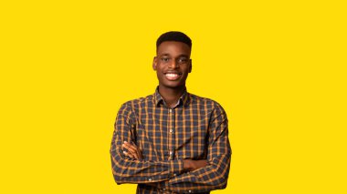 Sarı Stüdyo 'nun arkasında kıvrımlı kollarıyla poz veren, damalı tişört giyen, gülümseyen ve fotokopi ile Panorama' ya bakan yakışıklı Afrikalı Amerikalı bir adam.