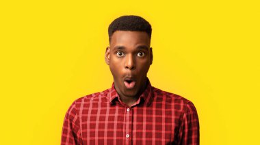 Şaşırmış Afrikalı Amerikalı adamın portresi Şaşırmış ve etkilenmiş görünen siyah milenyum adamı şaşırttı, sarı arka plandaki haberlere duygusal tepki verdi,