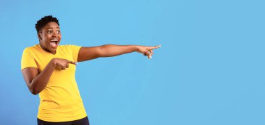 Şuraya bak. Aşırı kilolu Afrikalı Kadın Mavi Arkaplan 'ın üzerinde duran mesaj için boş yeri işaret ediyor. Reklam afişi. Panorama, Stüdyo Çekimi