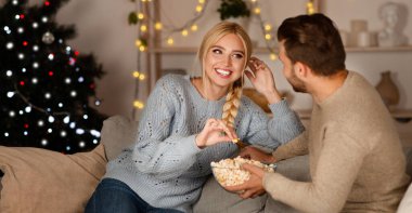 Neşeli erkek ve kadın kış tatillerinde evde vakit geçirir, patlamış mısır yer ve güler, mekanı kopyalarlar.