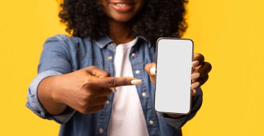 Elinde boş ekranla akıllı telefonu işaret eden siyah bir kadın, kesilmiş. Tanımlanamayan Afro-Amerikalı kadın modern cep telefonunu boş ekran, yakın çekim, maket