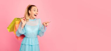 Omg, alışveriş teklifi konsepti. Terfi için fotokopi uzayını işaret eden Duygusal Kadın Portresi, Pastel Pembe Arka plan Stüdyoda, Banner 'da, Panorama' da izole edilmiş renkli çantalar taşıyor.