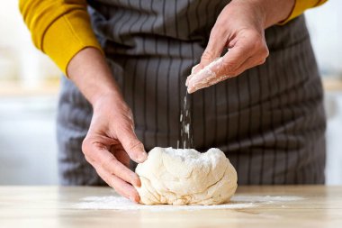 Kadın eli hamur yoğurur, un ekler, önlüklü, mutfakta yemek pişiren, hamur işi, kurabiye, pasta ya da turta yapan, pizza yapan tanınmamış bir kadın. Mutfak, yemek pişirme, pişirme konsepti