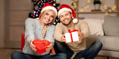 Kırmızı Noel Baba şapkalı mutlu koca ve eş evde birlikte yeni yılı kutluyorlar, hediyeler tutuyorlar, kameraya bakıyorlar, gülümsüyorlar, boşluk bırakıyorlar. Neşeli adam ve kadın hediye kutularını açıyor, Mutlu yıllar.