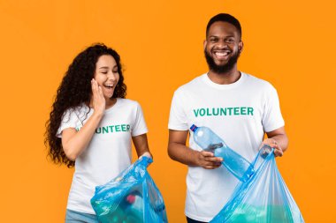 Heyecanlı Çok Kültürlü Kadın ve Erkek Gönüllüler Çöp Torbasından Plastik Şişe Topluyor Çevre Temizleme ve Çöp Toplama Sarı Arkaplanda Duran Çöp Toplama Stüdyo Çekimi