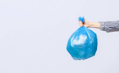 Kadın eli, çevre dostu alışkanlıkları savunurken mavi bir geri dönüşüm çantası sergiliyor. Arkaplanda, sürdürülebilirlik ve sorumlu atık yönetimi, kopyalama alanı konusundaki kararlılığı vurgulanıyor