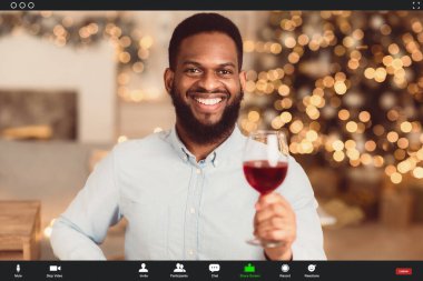Evde güvende ol, sosyal uzaklık, izolasyon. Neşeli mutlu siyahi adam internette konuşuyor, partneriyle internetten romantik bir randevu yaşıyor, elinde bir kadeh kırmızı şarap ve tost kadehi, monitör görüntüsü var.
