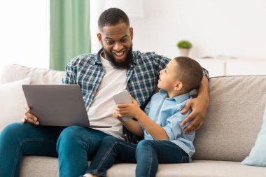 Kara Baba ve Oğlu, Gadget 'ları kullanarak heyecanlı babayı tablet bilgisayarla oturtup internette birlikte gezinirken gösteren çocuk. Teknoloji, Aygıtlar ve Modern Aile Yaşam Tarzı