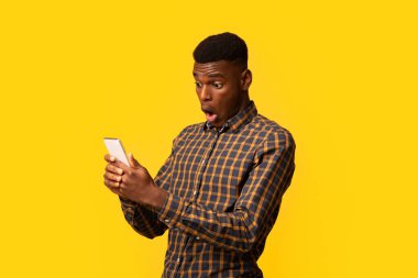 Şok olmuş komik zenci adamın portresi. Akıllı telefon ekranına bakıyor. Ağzı açık. Heyecanlı bir Afrikalı Amerikalı, iyi bir internet teklifine duygusal tepki veriyor.
