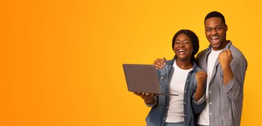Çevrimiçi Kazanan. Heyecanlı Afrikalı Amerikalı çift laptopla başarıyı kutluyor duygusal siyahi adam ve kadın yumruklarını kaldırıyor ve neşeyle bağırıyor sarı arkaplanda izole edilmiş, boşluğu kopyalıyor.