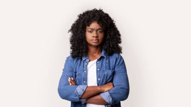 Gri stüdyo arka planında kollarını kavuşturmuş kıvırcık saçlı binlerce yıllık güzel Afro-Amerikan kadın portresi, kopya alanı. Kadın güzellik konsepti, kadın çeşitliliği