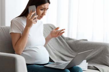 Evde dizüstü bilgisayarla uzaktan çalışan ve cep telefonuyla konuşan stresli kadın, endişeli kadın sorunları, oturma odasında koltukta oturmak, boşluğu kopyalamak...