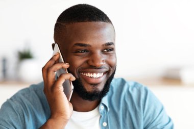 Memnun oldum. Milenyum siyahi adam cep telefonuyla konuşuyor ve gülümsüyor, neşeli Afrikalı Amerikalı adam telefon konuşmasından keyif alıyor, mutlu yüz ifadesini bir kenara atıyor, yakın çekim...