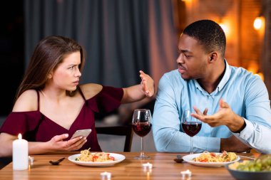 Lokantada romantik bir akşam yemeğinde akıllı telefon kullandığı için kız arkadaşını suçlayan kızgın siyah adam, el hareketlerini durduran genç kadın, çok kültürlü bir çiftin ilişki sorunları var.