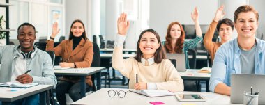 Grup Tartışması Konsepti. Gülümseyen Çeşitli Öğrenciler Kollarını kaldırıp Öğretim Görevlisine Bir Soru Soruyor, Üniversitede Ders Dinleyen Bilgisayarları Kullanıyor. Sınıftaki Çağdaş Öğrenciler çok ırklı