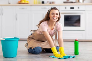 Mutfakta yerleri yıkayan genç ve mutlu ev kadınlarının tam boy portresi. Milenyum hizmetçisi ya da temizlikçi profesyonel temizlik hizmeti sunuyor, ev işlerini yapıyor, evini düzenli tutuyor.