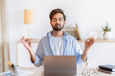 Çalışan Zen. Ofiste meditasyon yapan sakin bir iş adamı, masasında kapalı gözlerle otururken yoga yapan, Mudra 'da el ele tutuşan, iş yerinde stresle boğuşan, boş alanla uğraşan...