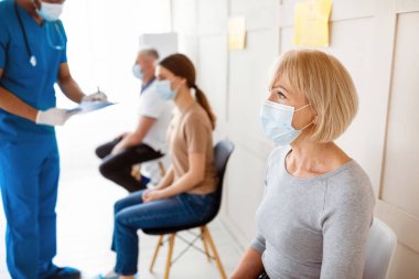 Kovid 19 aşısını bekleyen yaşlı bir kadın. Klinikte aşı olmadan önce hastaların sağlığını kontrol eden bir doktor. Coronavirus aşısı, viral hastalıklara karşı koruma kampanyası