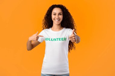 Sarı Stüdyo Arkaplanında Durup Kameraya Gülümseyen Kendini Gösteren Mutlu Kadın Gönüllü Hareketi. Kadın Eylemci Gönüllü Çalışmayı Onaylıyor Gibi Gösteriyor