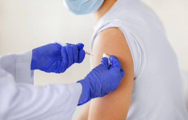 Genç erkek hastaya, klinikte koronavirüs aşısı enjekte edilirken görüntülenmiş. Tanımlanamayan doktor, milenyum insanını covid-19 virüsüne karşı bağışık hale getiriyor. Sağlık ve İlaç Hizmetleri