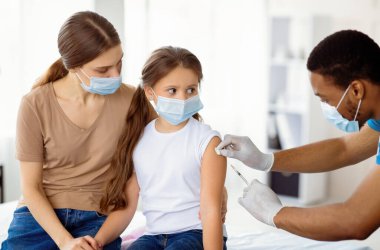 Tıbbi maskeli anne ve kız covid-19 aşısı oluyor, doktor hastanede koronavirüs aşısı yapıyor. Virüs aşılama karşıtı kampanya konsepti