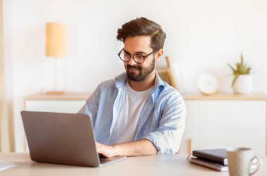 Gülümseyen Arap Girişimci, İçişleri Bakanlığı 'nda dizüstü bilgisayarla çalışıyor, online proje için bilgisayarını kullanıyor, Doğu Erkek Serbest Çalışan, Uzak İş Fırsatlarından keyif alıyor, Boşluğu Kopyalıyor