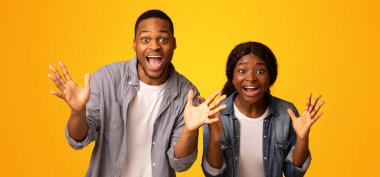 Heyecanla bağıran, sarı stüdyonun arka planına ellerini uzatan ve kameraya bakan, duygusal Afrikalı erkek ve kadının başarısını kutlayan, özgür uzay...