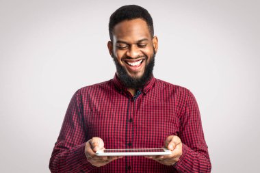 Beyaz Arkaplanda Dijital Tablet Tutan Afro-Amerikalı Neşeli Adam. Sakallı Siyah Adam Stüdyoda Bilgisayar Oyunu Oynuyor. Web sitesi, İnternet Servisi ve Yeni Uygulama Yönlendirmesi