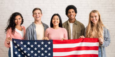 Göçmenlik, taşınma ve yurtdışında eğitim. Neşeli genç uluslararası öğrenciler kameraya bakıp öğrenmeye hazırlar. Beyaz tuğlalı arka planda, fotokopi alanında, stüdyo çekimlerinde.