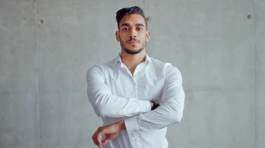 Genç, profesyonel bir Orta Doğulu, çağdaş ofis ortamında kendine güvenen bir adam. Kararlılık ve başarı havası sergiliyor. Doğal ışık modern arkaplanı güçlendirir.