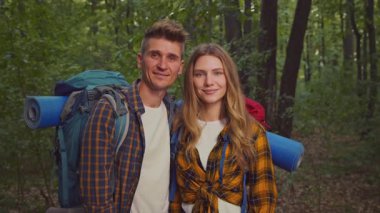 Bir çift, sakin bir ormanda kamp gezilerine başlamak için birlikte duruyorlar. Sırt çantaları, doğa güzelliğinin ortasında aktif bir yaşam tarzını kucakladıkları için temel ihtiyaçlarla dolu..